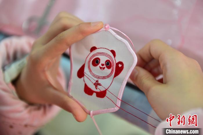 圖為一名小學(xué)生正在繡制2022年北京冬奧會(huì)吉祥物“冰墩墩”形象?！∮髟屏?攝