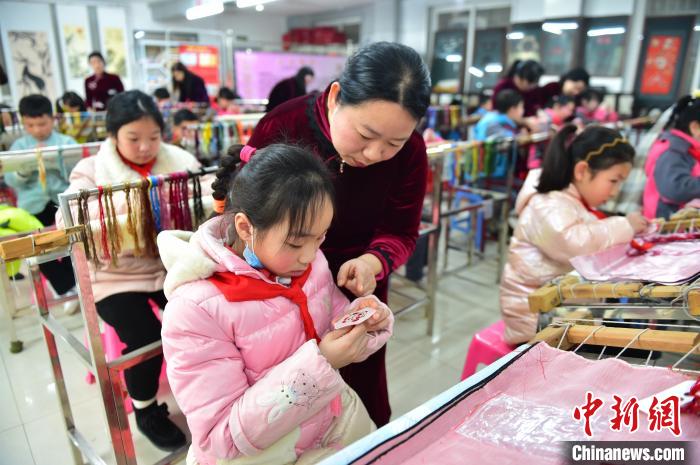 江西省級(jí)非遺豫章繡傳承人手把手指導(dǎo)小學(xué)生繡制2022年北京冬奧會(huì)吉祥物“冰墩墩”形象。　喻云亮 攝