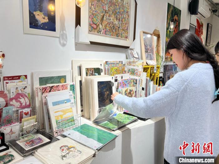 圖為藝術(shù)品商店內(nèi)，顧客挑選插畫作品。　鐘旖 攝