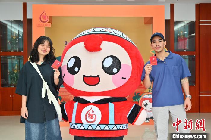 圖為泰國(guó)留學(xué)生手持獻(xiàn)血證與人偶合影?！∮峋?攝