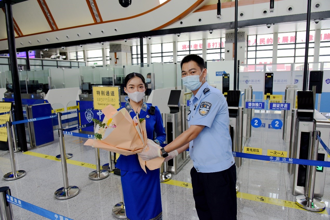 磨憨出入境邊防檢查站民警為中老鐵路第100萬(wàn)名出入境旅客，D888次國(guó)際旅客列車(chē)?yán)蠐爰藙?wù)員森達(dá)拉·妮緹婭（Sengdala Nitiya），送上鮮花。黃遠(yuǎn)飛 攝