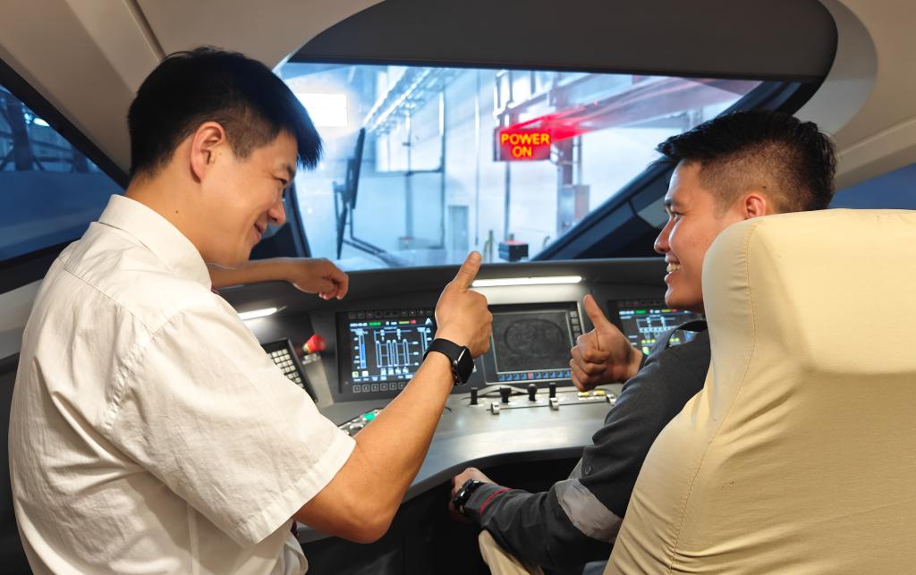 8月25日，在印度尼西亞萬隆的雅萬高鐵德卡魯爾動車所內(nèi)，中國師傅穆振（左）在向印尼火車司機塞蒂亞萬講解動車組出庫前的上電作業(yè)。
