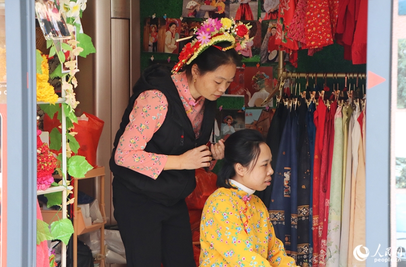 泉州府文廟附近，一名店主正為過(guò)路游客梳理頭發(fā)以佩戴“簪花圍”。人民網(wǎng) 黃東儀攝