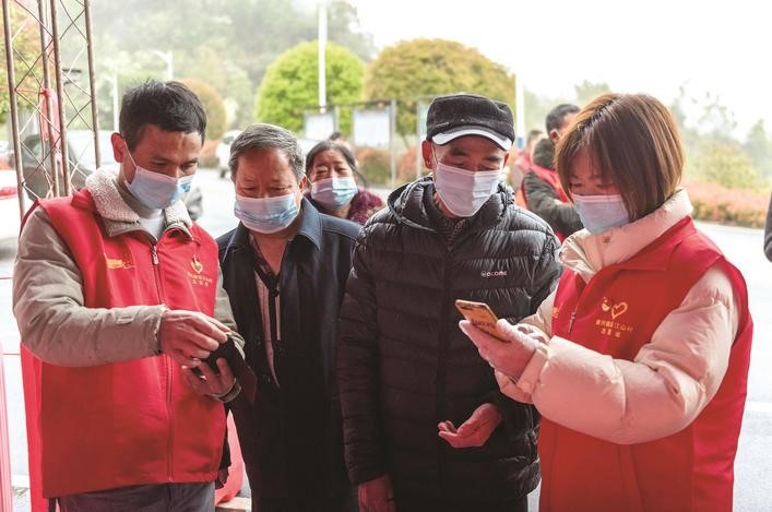 長(zhǎng)沙縣黨員志愿者正在幫助參與核酸檢測(cè)的群眾掃描“場(chǎng)所碼”。劉思源 攝