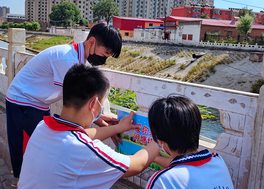 徐水小學(xué)學(xué)雷鋒志愿者在瀑河河邊張貼防溺水警示標(biāo)語(yǔ)。 徐水區(qū)委宣傳部供圖