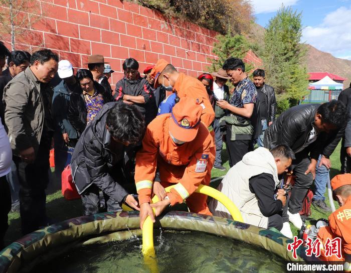 圖為森林消防員為護(hù)林員講解滅火裝備的使用方法?！〔际猩窒乐ш?duì) 供圖