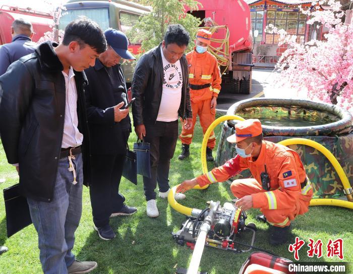 圖為森林消防員為護(hù)林員講解滅火裝備的使用方法?！〔际猩窒乐ш?duì) 供圖