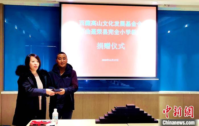 圖為西藏高山文化發(fā)展基金會(huì)理事長(zhǎng)溫麗向聶榮縣完全小學(xué)負(fù)責(zé)人捐助儀器?！∮谫e 攝
