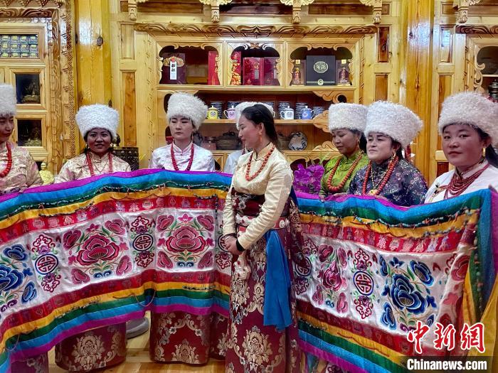 圖為女性展示村民自發(fā)繡制的“百米五彩哈達(dá)”?！±钣穹?攝
