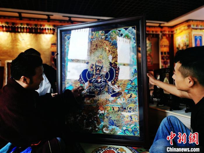 圖為久美尖措(左)與徒弟們展示唐卡作品?！?zhí)砀?攝