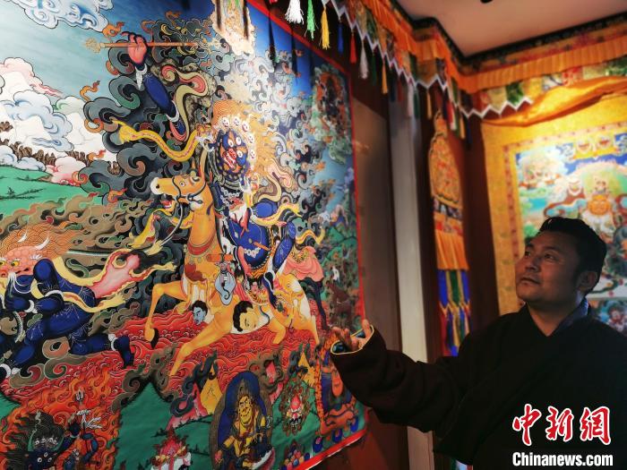 圖為久美尖措展示唐卡作品?！?zhí)砀?攝