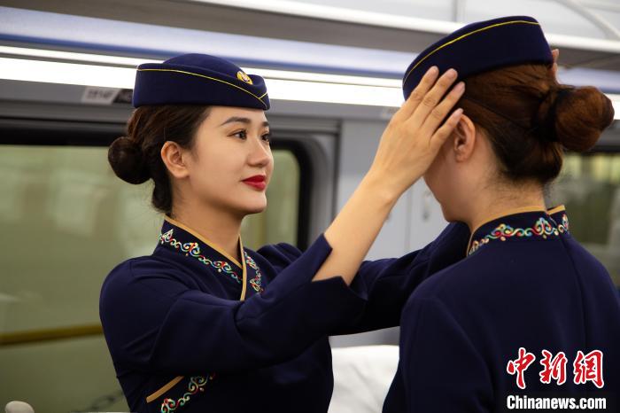 圖為青藏鐵路西格段“復(fù)興號(hào)”動(dòng)車(chē)組乘務(wù)員互相整理新制服?！±罾?攝