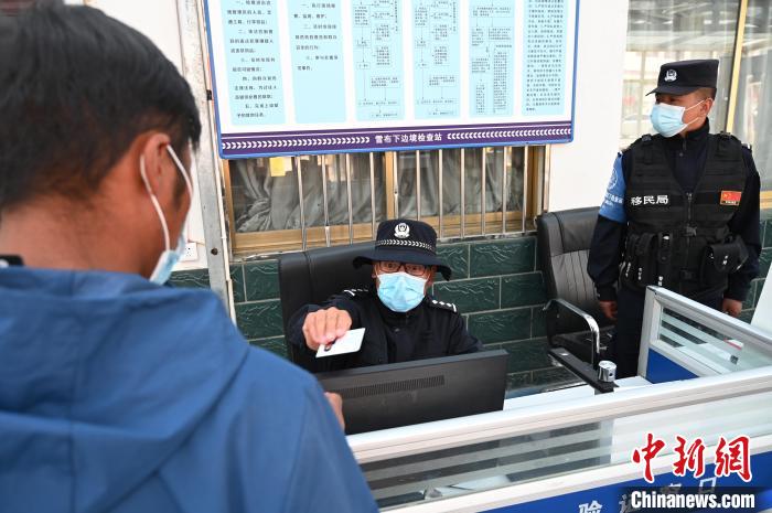 圖為移民管理警察登記完身份信息后將證件歸還給行人?！≮w朗 攝