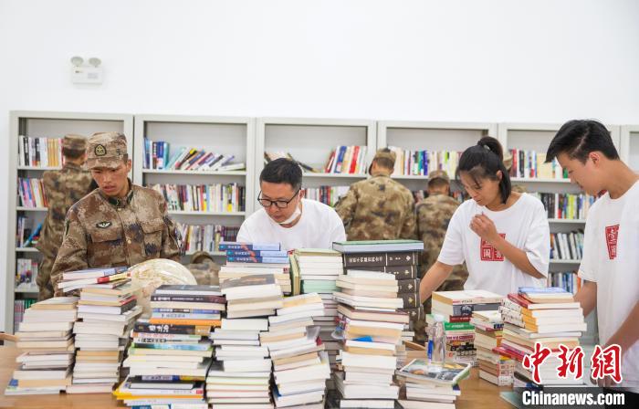 圖為志愿者們和邊防戰(zhàn)士整理圖書?！詵| 攝