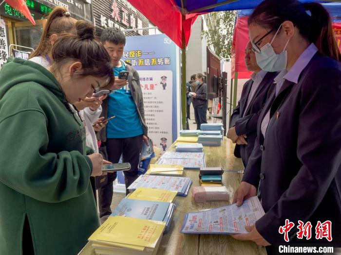 圖為工作人員正在向路過(guò)市民介紹國(guó)家反詐中心軟件的功能。　謝牧 攝