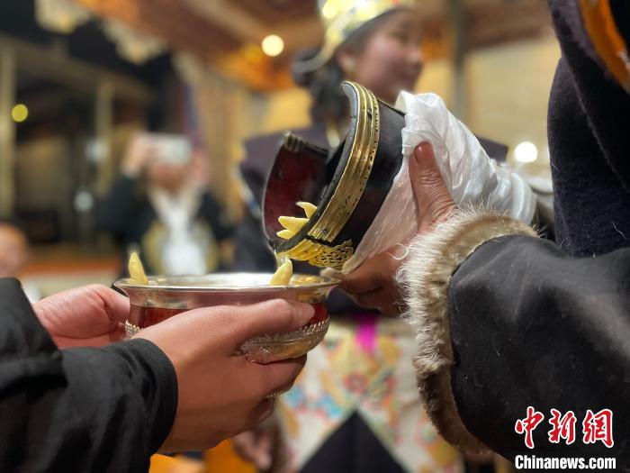 圖為主人在碗中斟滿青稞酒。　冉文娟 攝
