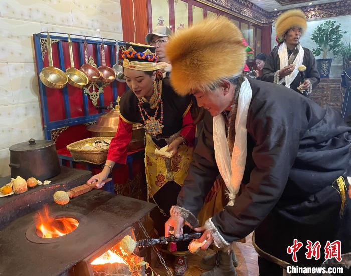 圖為人們在火上烤節(jié)日美食“結(jié)達(dá)”?！∪轿木?攝