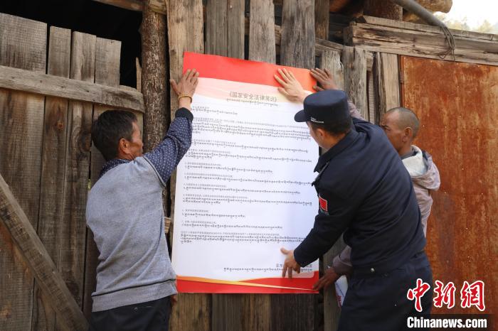 圖為亞?wèn)|邊檢站民警與駐地邊民群眾共同張貼國(guó)家安全知識(shí)教育海報(bào)。　亞?wèn)|邊檢站 供圖
