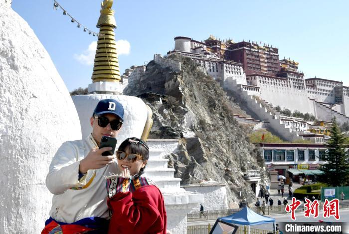 4月17日，游客身著藏式元素服裝在拉薩布達(dá)拉宮觀景臺(tái)拍照留念。　李林 攝