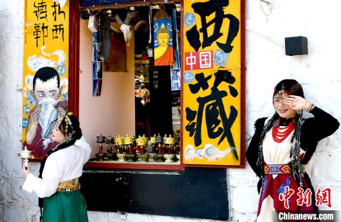 4月17日，游客身著藏式元素服裝在拉薩八廓街拍照留念。　李林 攝