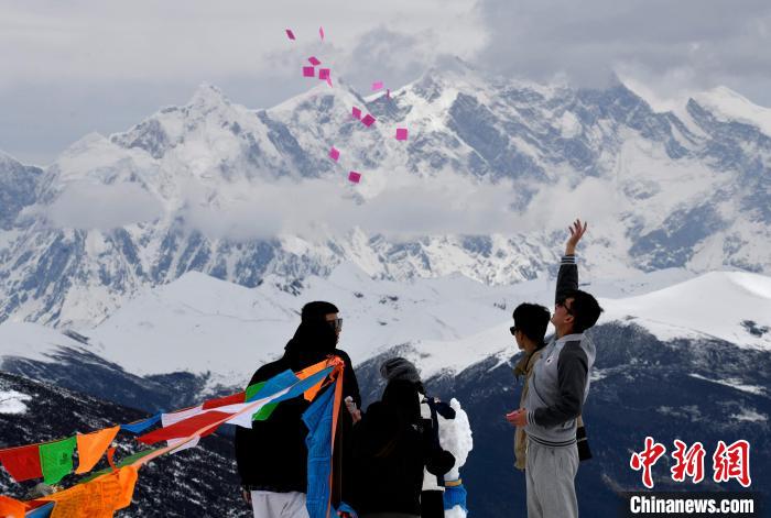圖為5月14日，游客在西藏林芝色季拉山觀景臺拋灑“隆達”(風馬旗，藏族民眾的一種祈福方式)。　李林 攝